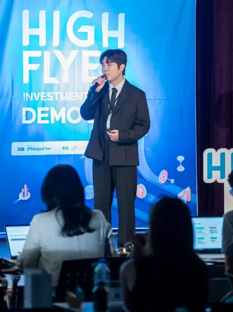 Youngtak Jo presenting on stage, holding a microphone